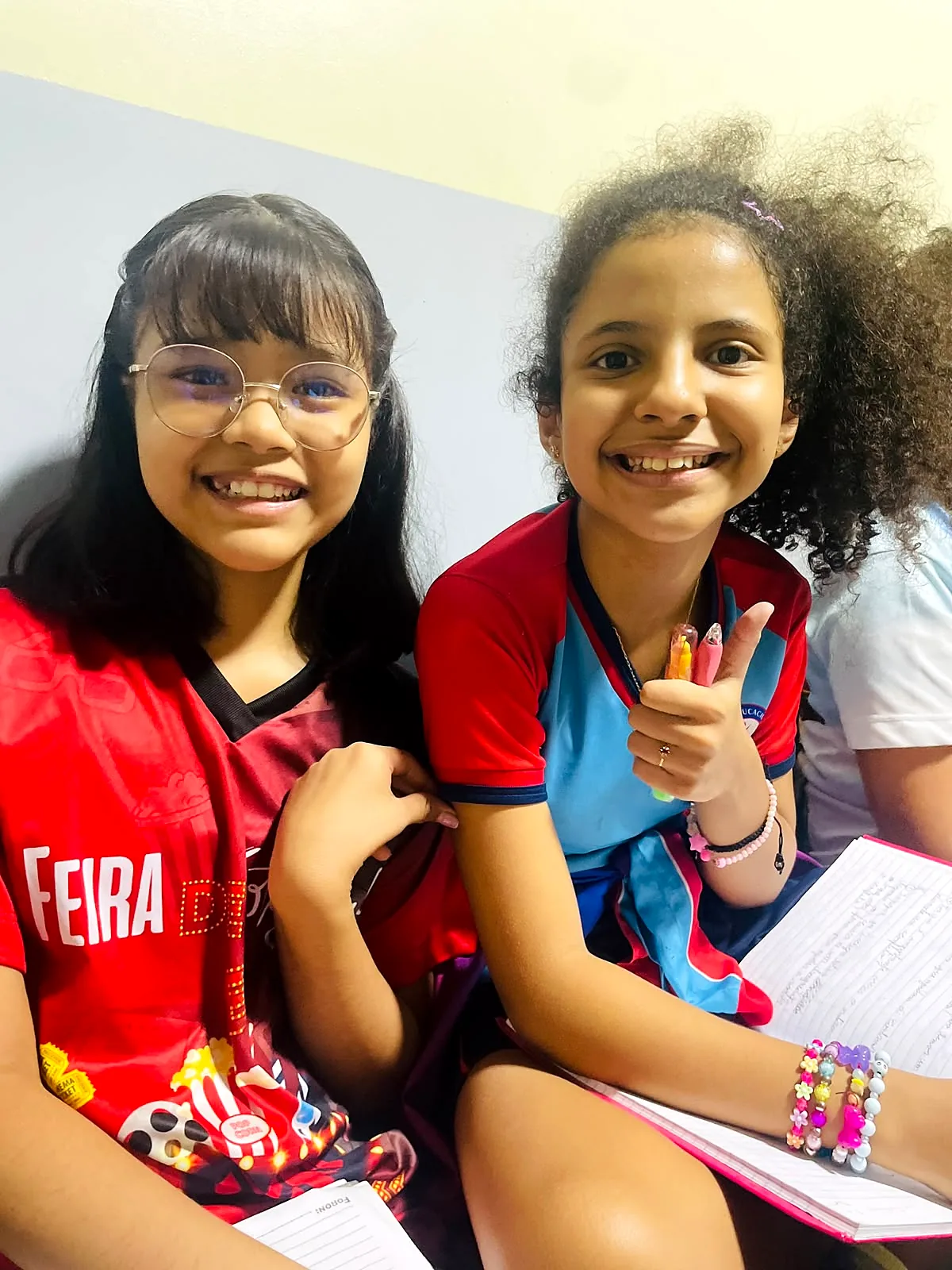 Duas alunas sorrindo durante atividade em sala