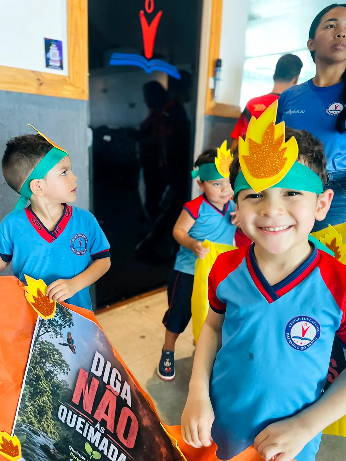 Alunos com coroas de fogo em papel e cartaz Diga não às queimadas, na caminhada da escola