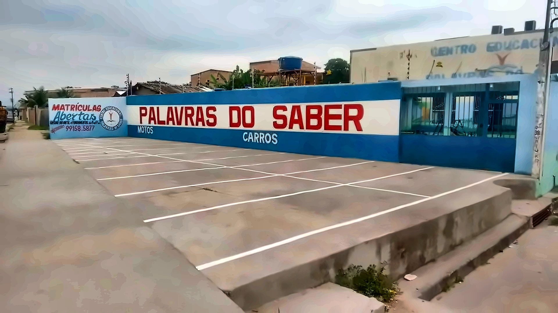 Fachada do Centro Educacional Palavras do Saber, com o muro azul e o estacionamento próprio para carros e motos