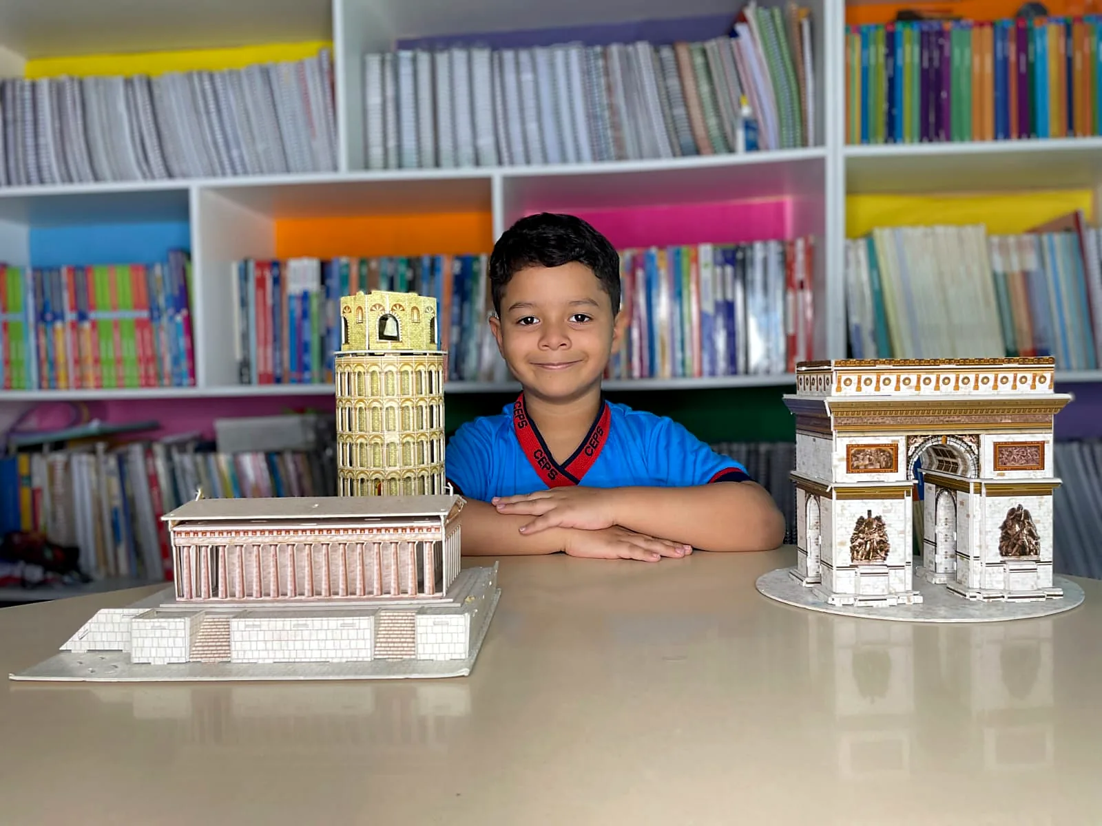 Aluno na biblioteca da escola com maquetes de monumentos feitas em projeto