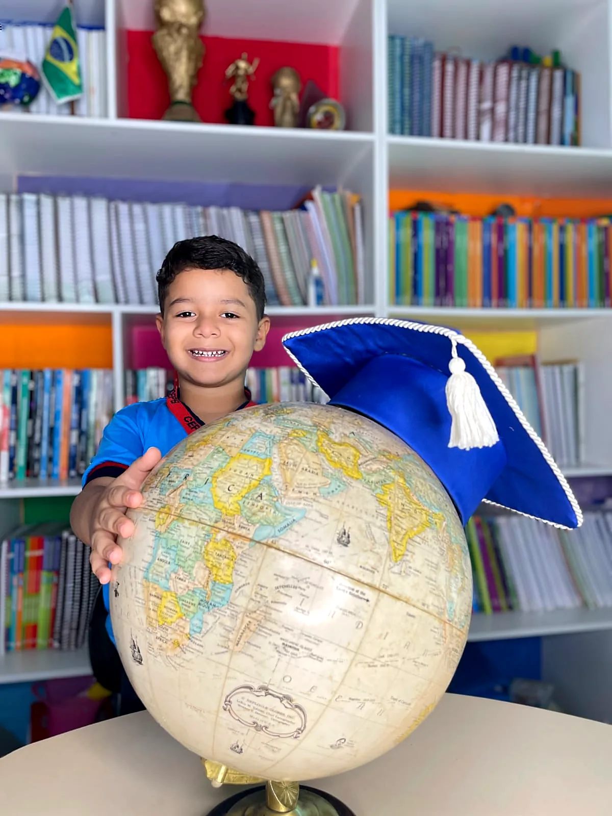Aluno na biblioteca da escola segurando um globo terrestre